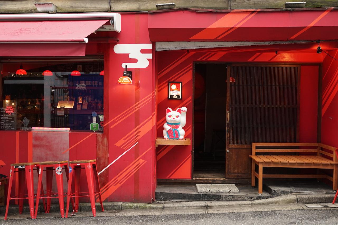 古民家をリニューアルしたバー「渋谷花魁」の外観。真っ赤な外壁や赤いベンチ、猫の置物などが並んでいる。